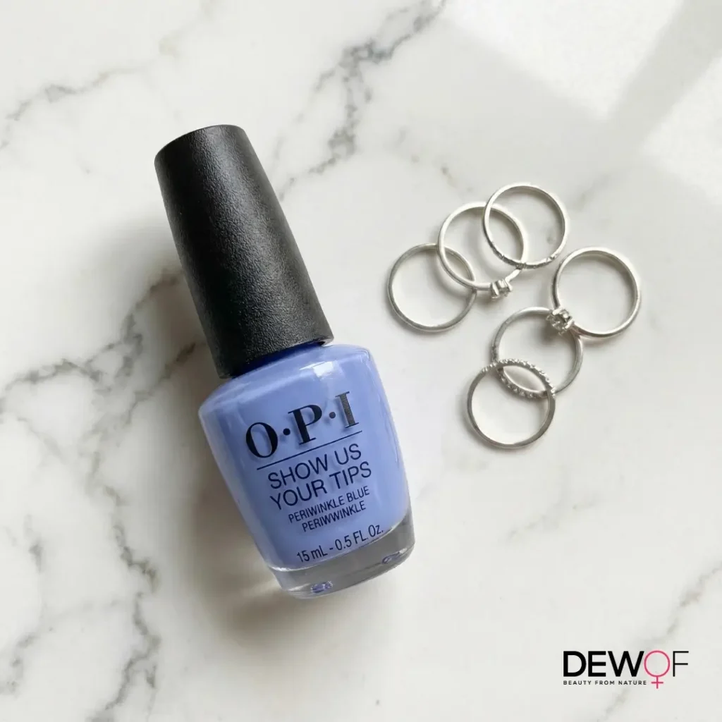 OPI periwinkle nail polish bottle “Show Us Your Tips” on marble with silver rings, highlighting best periwinkle nail polish colors and designs.